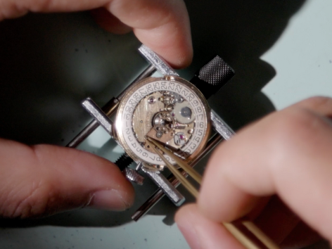A person repairing a watch with precision tools and careful hands.